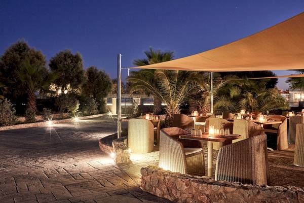 Außenbereich des Santo Miramare Resorts bei Nacht mit beleuchteten Tischen und Palmen.