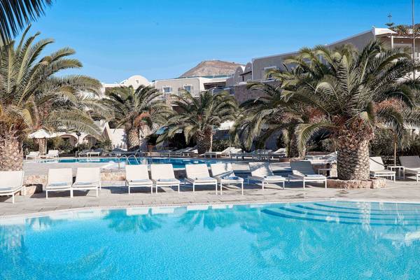 Pool-Loungebereich im Santo Miramare Resort mit weißen Liegestühlen und Palmen.