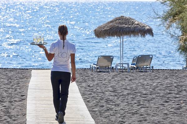 Mitarbeiterin im Santo Miramare Resort auf dem Weg am Strand mit Getränken.