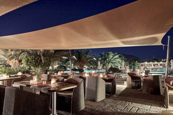 Außenrestaurant des Santo Miramare Resorts bei Nacht mit illuminiertem Swimmingpool im Hintergrund.