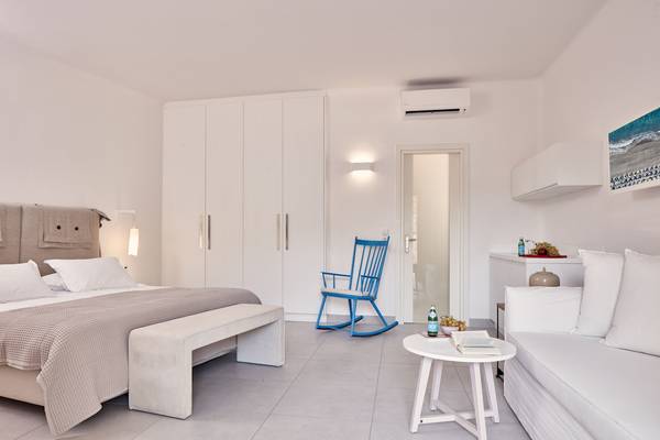 Schlafzimmer im Santo Miramare Resort mit Bett, Sessel, Tisch und Klimaanlage