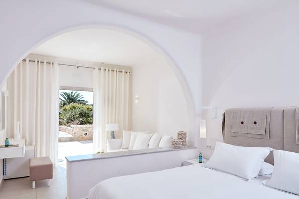 Innenansicht eines Zimmers im Santo Miramare Resort mit weißem Bett und Fenstern