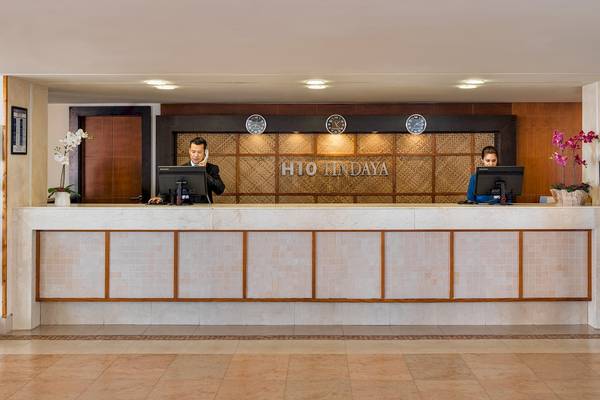 Die Rezeption des H10 Tindaya Hotels mit zwei Angestellten und dekorativen Pflanzen.