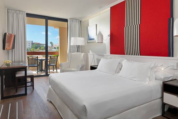 Hotelzimmer im H10 Tindaya mit Doppelbett, Sessel und Terrassenblick.