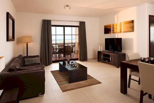 Wohnzimmer des Melia Tortuga Beach Hotels mit Sofa, Tisch, Fernseher und Balkon.