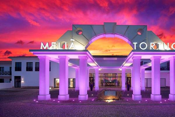 Der Eingang des Melia Tortuga Beach Hotels bei Nacht mit lila Beleuchtung und einem roten Himmel.