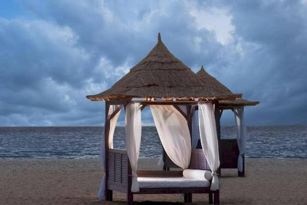 Ein Zeltbett am Strand des Melia Tortuga Beach Hotels mit Blick auf das Meer und einen bewölkten Himmel.