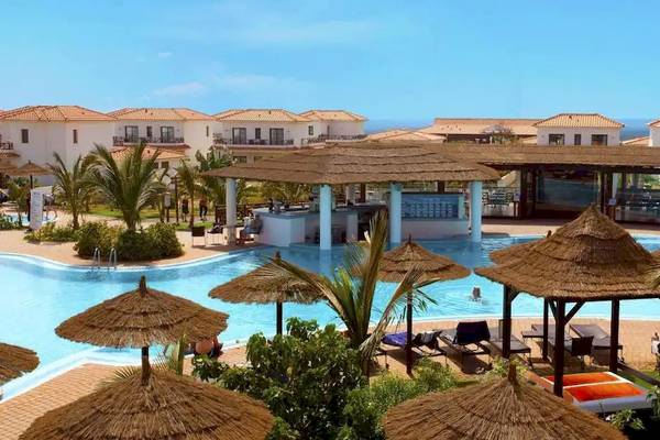 Außenbereich des Melia Tortuga Beach Resorts mit Swimmingpool, Sonnenliegen und Strohhütten.