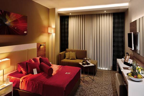 Suite-Zimmer im White City Resort mit rotem Bett, Sofa und Tisch mit Früchten.
