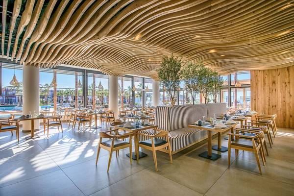 Innenansicht des Restaurants im Stella Island Luxury Resort & Spa mit hölzerner Decke und modernen Möbeln.