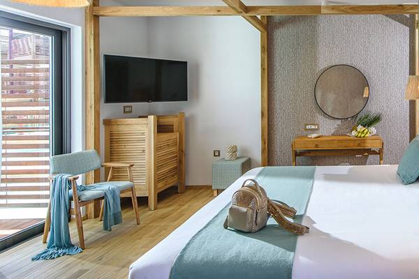 Innenansicht eines Zimmers im Stella Island Luxury Resort & Spa Hotel mit Bett, Möbeln und Fernseher.