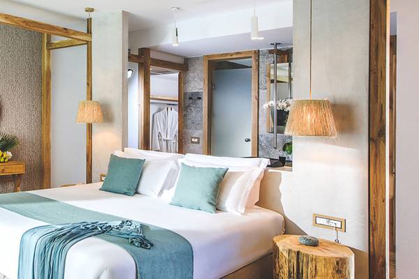 Luxuriöses Schlafzimmer im Stella Island Luxury Resort & Spa mit Bett, Kissen, Nachttisch und Spiegel.