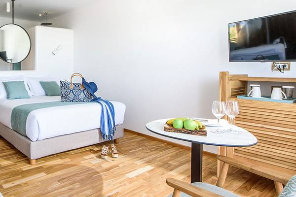 Luxuriöses Hotelzimmer im Stella Island Luxury Resort & Spa mit Bett, Tisch, Fernseher und moderner Einrichtung.