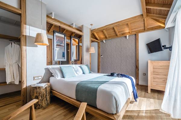 Innenansicht des Schlafzimmers im Stella Island Luxury Resort & Spa Hotel mit Holzboden, Bett und Möbeln.