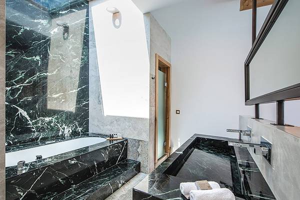 Luxuriöses Badezimmer im Stella Island Luxury Resort & Spa mit schwarzem Marmor und weißen Handtüchern.