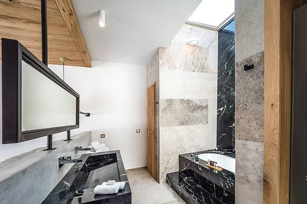 Badezimmer des Stella Island Luxury Resort & Spa mit schwarzem Marmor und Badewanne