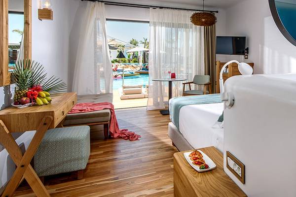 Innenansicht einer Suite im Stella Island Luxury Resort & Spa mit Swimmingpool im Hintergrund.