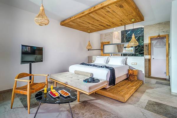 Innenansicht der Suite im Stella Island Luxury Resort & Spa mit Bett, Fernseher und Frühstückstablett.