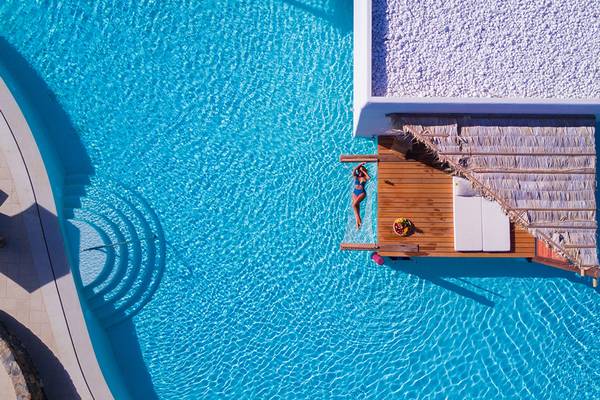 Aussenansicht des Stella Island Luxury Resort & Spa mit Infinity-Pool und Liegewiese.