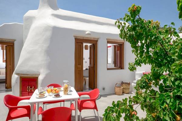 Frühstückstisch auf der Terrasse der Villa Romantica mit rotem Stuhl und Frühstücksbuffet.