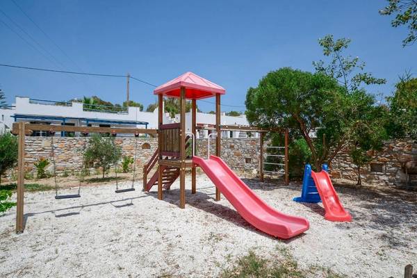 Spielplatz der Villa Romantica mit roten und blauen Rutschen und Schaukeln vor einem Gebäude