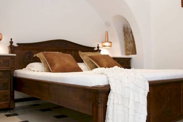 Schlafzimmer in der Villa Romantica mit Holzbett, weißen Laken, braunen Kissen und zwei kupfernen Lampen.