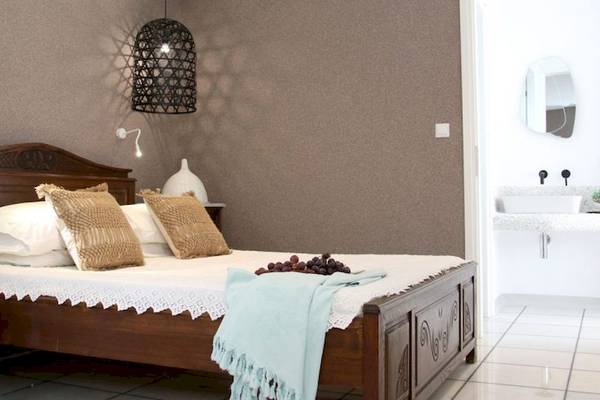 Schlafzimmer der Villa Romantica mit einem großen Bett, dekorativen Kissen und einem blauen Plaid.