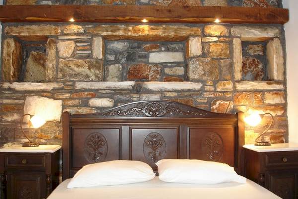 Schlafzimmer in der Villa Romantica mit Steinwand, betten und Nachttischen.