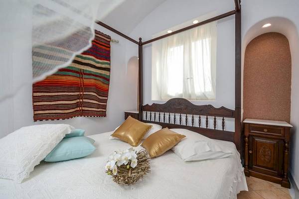 Schlafzimmer in der Villa Romantica mit einem vierposterbett, blumengestecke und bunten decken