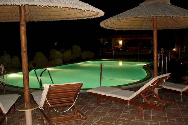Pool der Villa Romantica bei Nacht mit zwei Liegestühlen und Sonnenschirmen