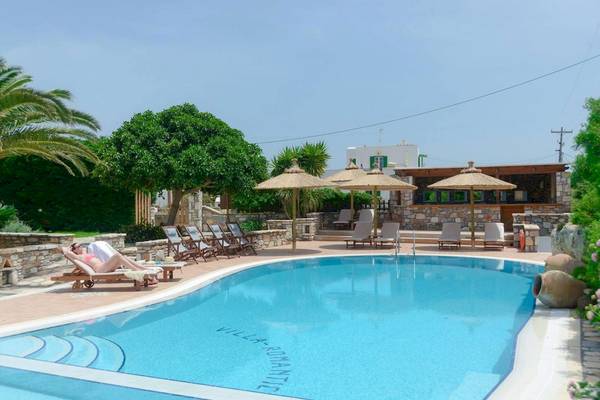 Ein Swimmingpool im Freien mit Liegestühlen und Sonnenschirmen, ein Hotelgast entspannt sich.