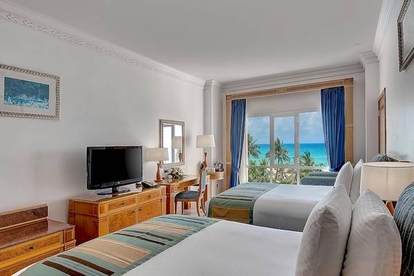 Doppelzimmer im Crowne Plaza Resort Salalah mit Meerblick, zwei Betten, Fernseher, Schreibtisch und Ausblick auf das Meer.
