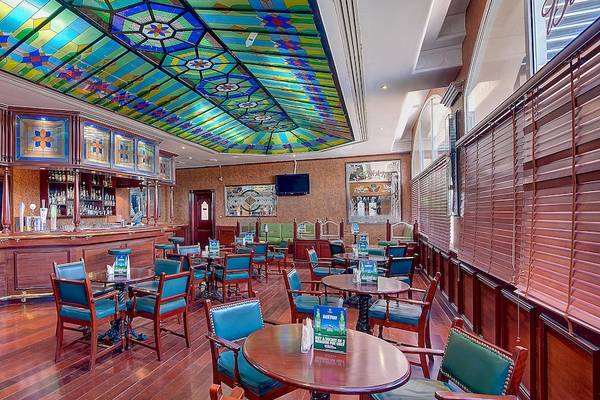 Innenansicht des Crowne Plaza Resort Salalah Bar mit Holzboden, bunten Stühlen und Tischen.