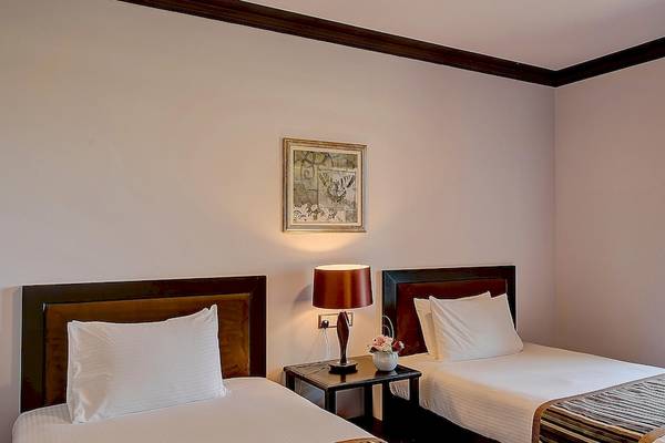 Zwei Betten in einem Zimmer im Crowne Plaza Resort Salalah mit Aussicht auf Palmen und Meer.