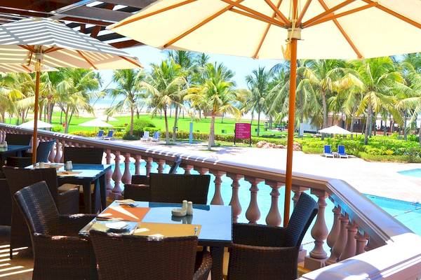 Poolterrasse des Crowne Plaza Resort Salalah mit Tischen, Stühlen und Sonnenschirmen