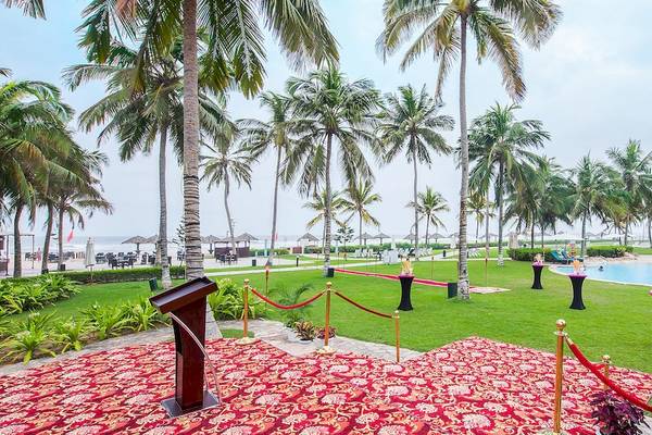 Außenbereich des Crowne Plaza Resort Salalah mit rotem Teppich, roten Seilen und Palmen.