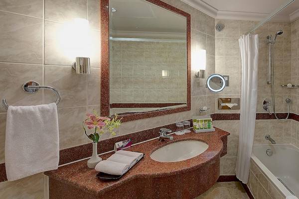 Badezimmer im Crowne Plaza Resort Salalah mit Badewanne, Spiegel und Waschbecken.