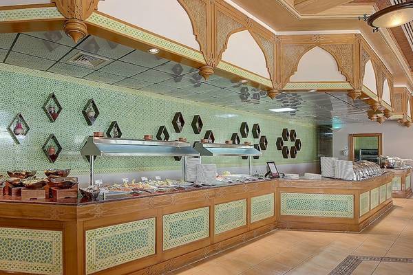 Innenbereich des Restaurants im Crowne Plaza Resort Salalah mit grünen Fliesen und Holzdekoration.