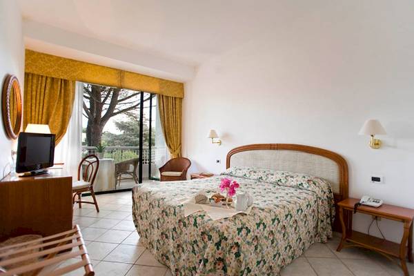 Ein Schlafzimmer im Sierra Silvana Hotel mit Balkon, Fernseher, und Blumenbettwäsche.