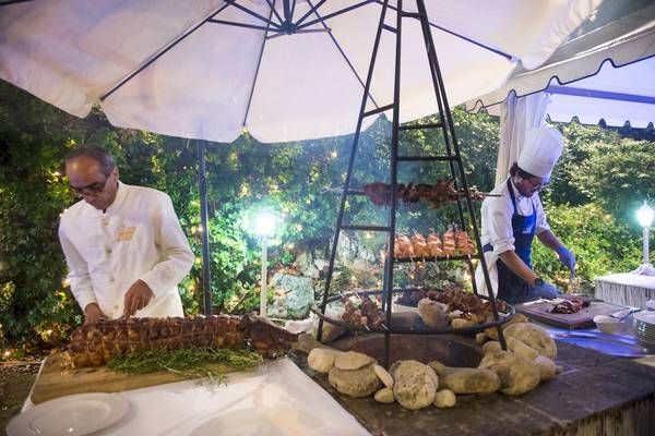 Zwei Köche bereiten Speisen auf einem Grillbereich im Freien im Hotel Sierra Silvana zu.