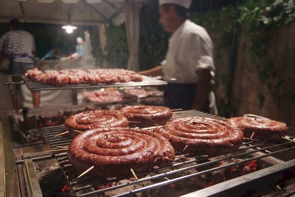 Grillen im Hotel Sierra Silvana mit einem Koch, der Würstchen auf einem Grill zubereitet.