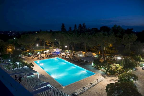 Luftaufnahme des beleuchteten Außenpools und der Terrasse des Hotels Sierra Silvana bei Nacht