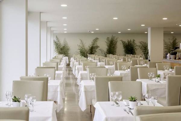 Restaurant des Alkyna Lifestyle Beach Resorts mit weißen Tischen und Stühlen, Pflanzen und Deckenlampen.