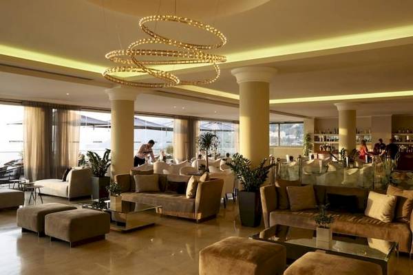 Lobby des Alkyna Lifestyle Beach Resorts mit Möbeln, Pflanzen und einer Person, die serviert.