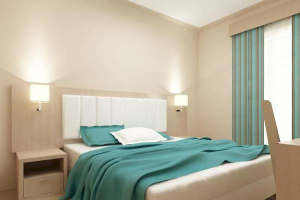 Schlafzimmer im Alkyna Lifestyle Beach Resort mit einem Bett, Kissen, Nachttisch und Wandlampen.