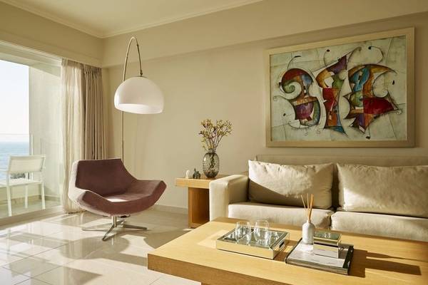 Wohnzimmer des Alkyna Lifestyle Beach Resort mit Couch, Stuhl, Tisch, Lampe und Gemälde.