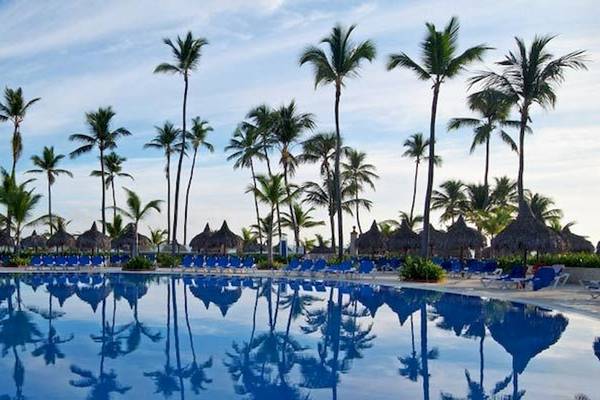 Ein großer Swimmingpool des Bahia Principe Grand Bavaro Hotels, umgeben von Palmen und Sonnenliegen.