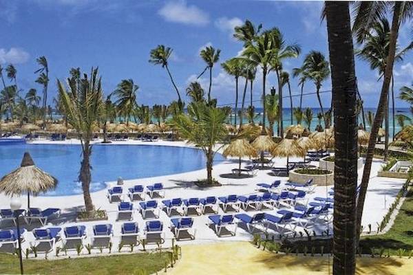 Außenbereich des Bahia Principe Grand Bavaro Hotels mit Swimmingpool, Sonnenliegen und Palmen.