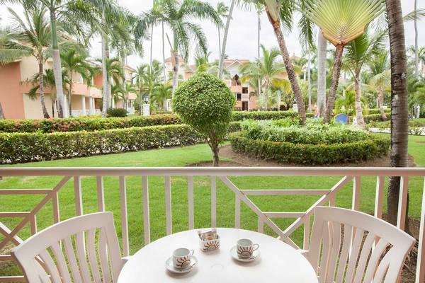Terrasse mit Blick auf den Rasen und Palmen des Bahia Principe Grand Bavaro Hotel.