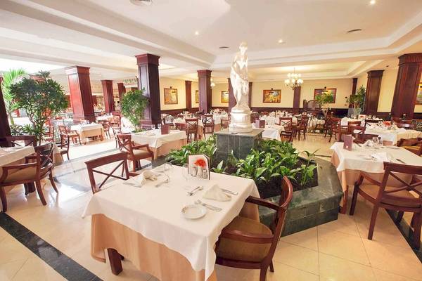 Restaurant im Bahia Principe Grand Bavaro mit Tisch, Statue und Pflanzen.
